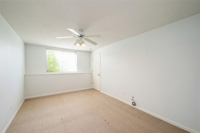unfurnished room featuring ceiling fan, light colored carpet, baseboards, and a textured ceiling
