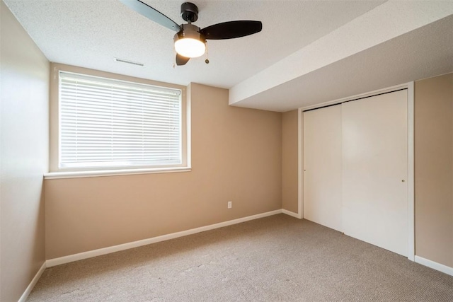 unfurnished bedroom with carpet floors, a closet, baseboards, and a ceiling fan