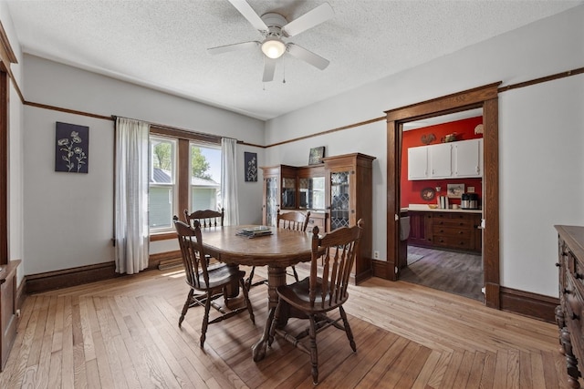 dining space featuring ceiling fan, light wood finished floors, a textured ceiling, and baseboards