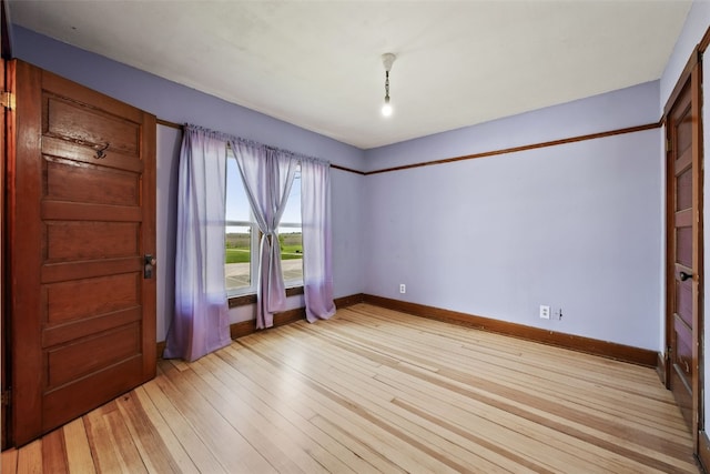 empty room featuring light wood-type flooring and baseboards