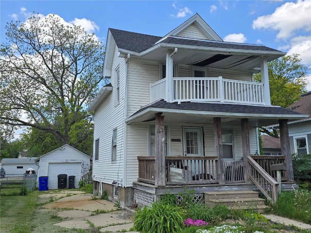 view of front of home with covered porch, a balcony, a garage, an outbuilding, and driveway