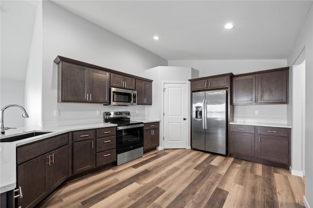 3850 Quail Trail Dr, Marion, IA 52302 - kitchen featuring stainless steel appliances, a sink, vaulted ceiling, dark brown cabinets, and light countertops