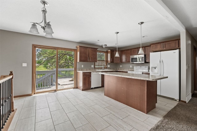 kitchen with white appliances, a center island, a sink, and hanging light fixtures