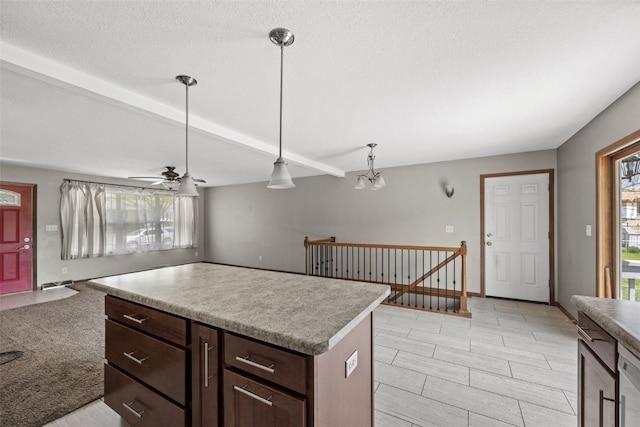 kitchen featuring a ceiling fan, decorative light fixtures, light countertops, a kitchen island, and open floor plan