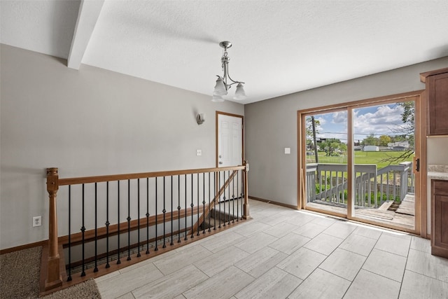 unfurnished room featuring a chandelier, baseboards, and a textured ceiling