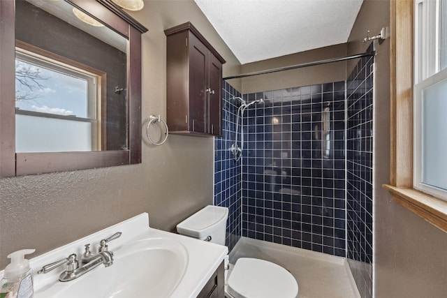full bathroom with toilet, tiled shower, vanity, and a textured ceiling