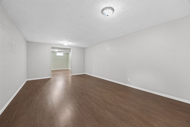 unfurnished room with dark wood-style flooring, a textured ceiling, and baseboards
