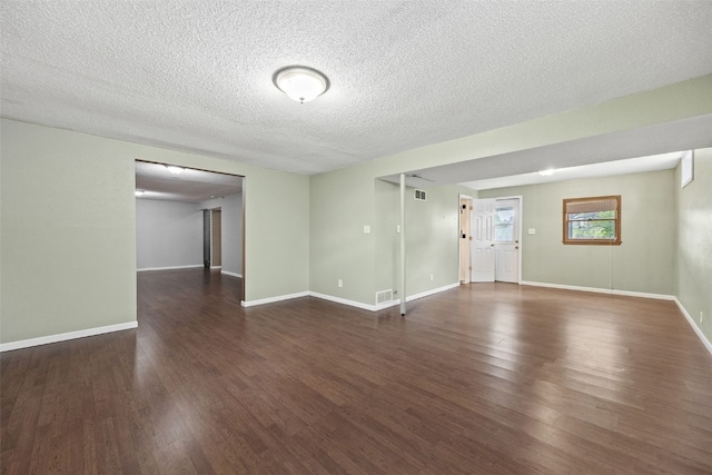 unfurnished living room with wood finished floors, a textured ceiling, and baseboards