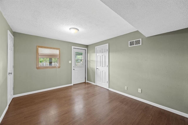 unfurnished room featuring a textured ceiling, baseboards, and wood finished floors