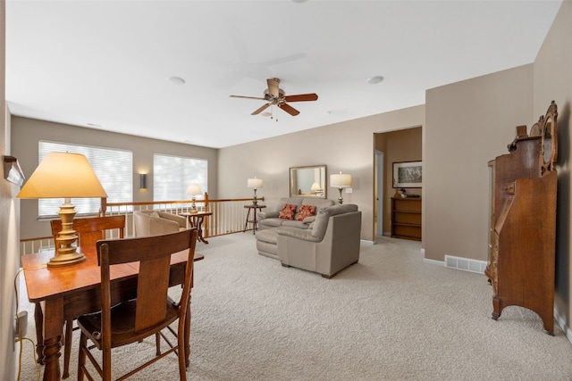 living area with ceiling fan, light colored carpet, and baseboards