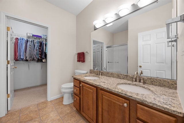 full bath featuring a stall shower, double vanity, a spacious closet, toilet, and baseboards