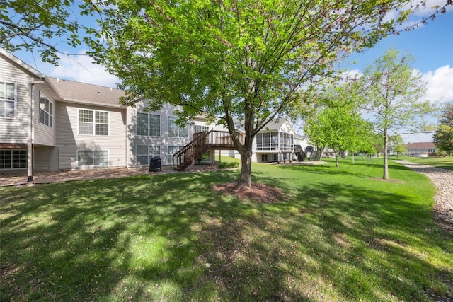 view of grassy yard with stairs and a deck