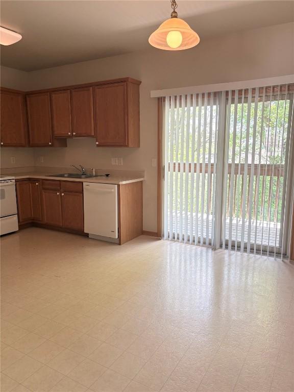 kitchen featuring white dishwasher, range, a sink, light countertops, and decorative light fixtures