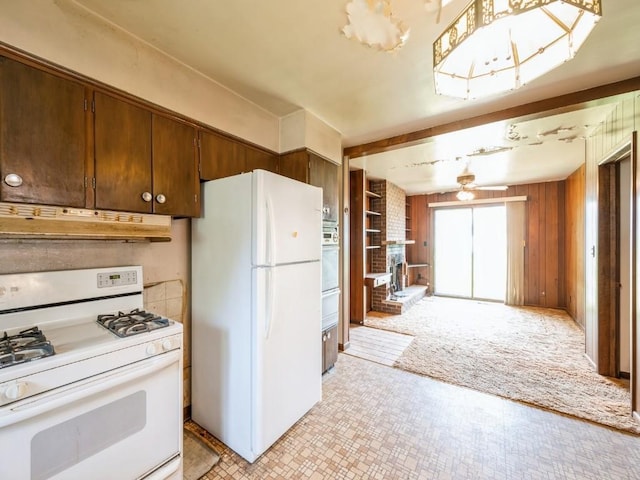 kitchen featuring white appliances, under cabinet range hood, a ceiling fan, a warming drawer, and a brick fireplace