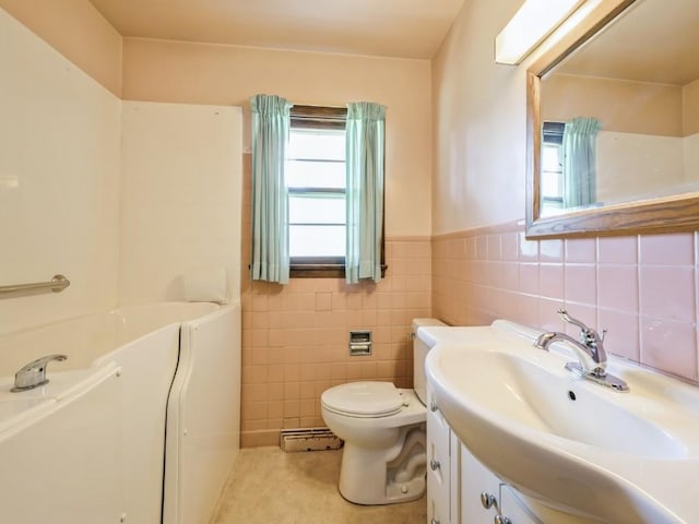 bathroom with tile walls, a baseboard radiator, vanity, toilet, and wainscoting