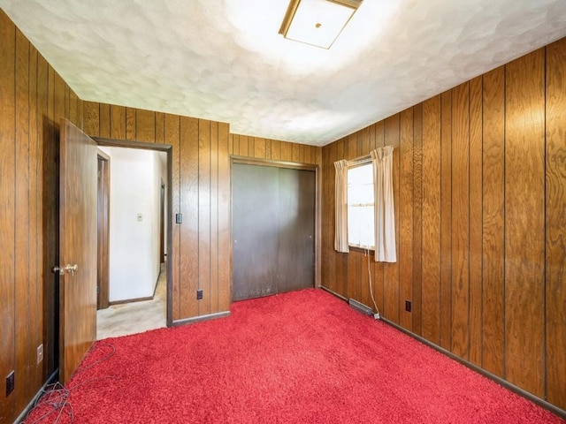 carpeted spare room featuring wood walls