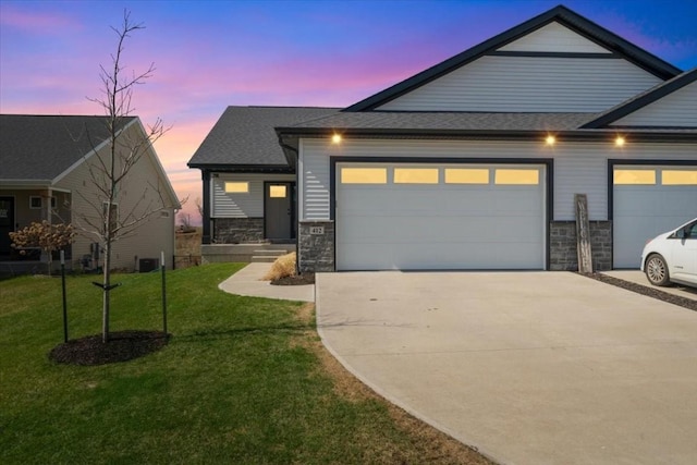 412 Dawson Dr, West Branch, IA 52358 - view of front facade with concrete driveway, stone siding, a garage, and a lawn