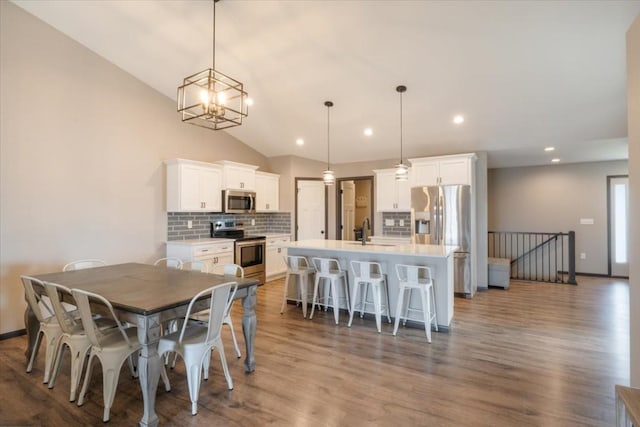 412 Dawson Dr, West Branch, IA 52358 - dining room with wood finished floors, vaulted ceiling, recessed lighting, baseboards, and a chandelier