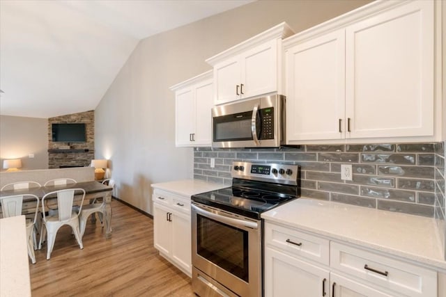 412 Dawson Dr, West Branch, IA 52358 - kitchen featuring appliances with stainless steel finishes, lofted ceiling, decorative backsplash, light wood-style flooring, and white cabinetry