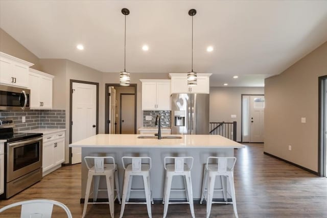 412 Dawson Dr, West Branch, IA 52358 - kitchen with appliances with stainless steel finishes, a sink, decorative backsplash, dark wood finished floors, and recessed lighting