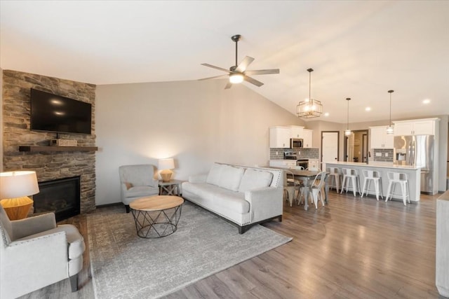 412 Dawson Dr, West Branch, IA 52358 - living room with ceiling fan, a stone fireplace, wood finished floors, lofted ceiling, and recessed lighting