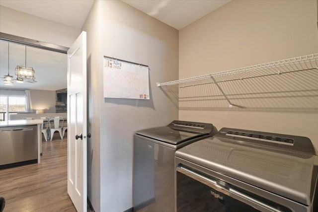 412 Dawson Dr, West Branch, IA 52358 - washroom featuring wood finished floors, washing machine and dryer, and a chandelier