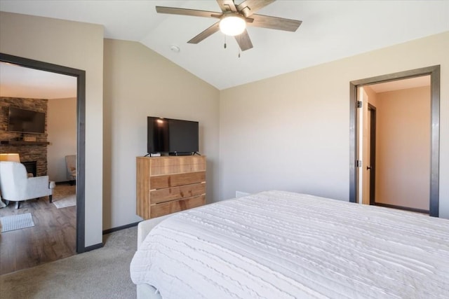 412 Dawson Dr, West Branch, IA 52358 - carpeted bedroom featuring vaulted ceiling, a stone fireplace, and a ceiling fan
