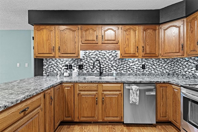 206 Hilltop Rd SW, Swisher, IA 52338 - kitchen with stainless steel dishwasher, a sink, stove, brown cabinets, and a textured ceiling