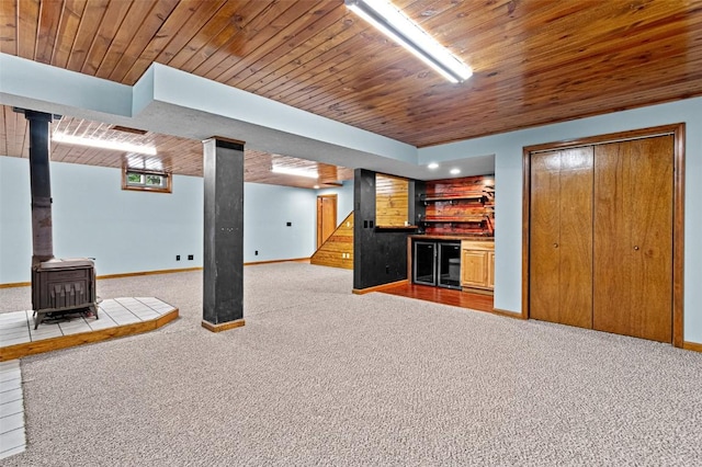 206 Hilltop Rd SW, Swisher, IA 52338 - unfurnished living room featuring a wood stove, wood ceiling, bar area, carpet flooring, and baseboards