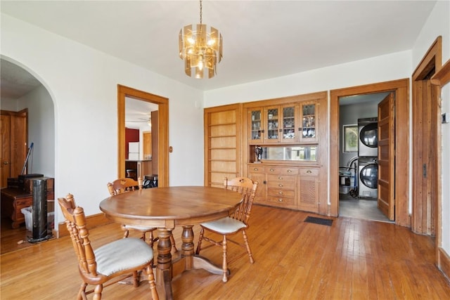 829 Union Ave, Lowden, IA 52255 - dining space with stacked washer / drying machine, arched walkways, a chandelier, and light wood-type flooring