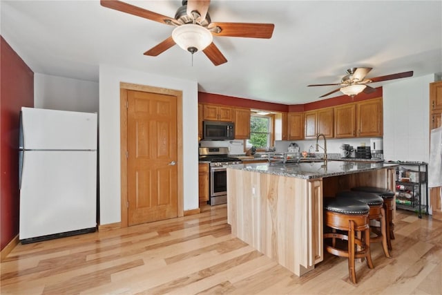 829 Union Ave, Lowden, IA 52255 - kitchen featuring freestanding refrigerator, stainless steel range with gas cooktop, a ceiling fan, and light wood-style flooring
