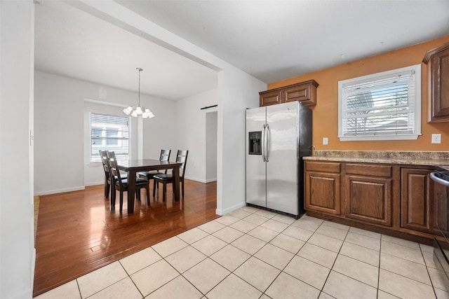 kitchen featuring stainless steel refrigerator with ice dispenser, a chandelier, light wood-type flooring, decorative light fixtures, and baseboards
