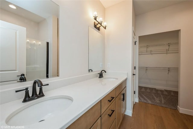 2559 Bluegrass St, Marion, IA 52302 - full bath with wood finished floors, a walk in closet, double vanity, baseboards, and recessed lighting