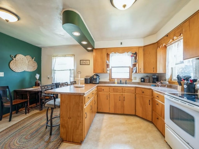 404 3rd St, Keystone, IA 52249 - kitchen featuring white electric range oven, a peninsula, a kitchen bar, and light countertops
