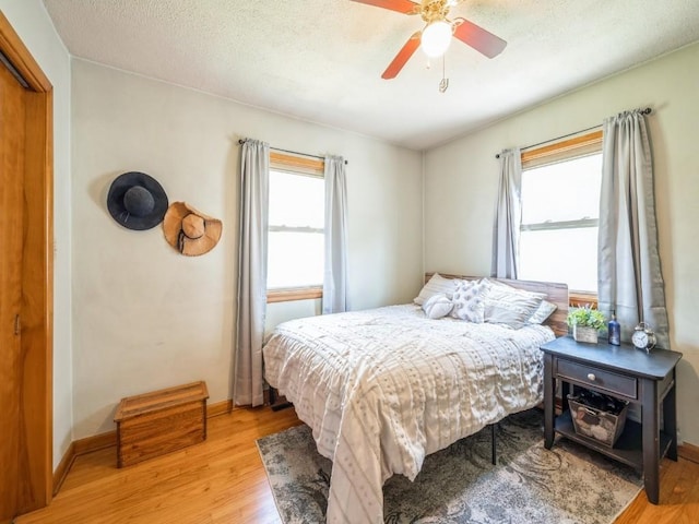 404 3rd St, Keystone, IA 52249 - bedroom featuring light wood-style flooring, multiple windows, a ceiling fan, and baseboards