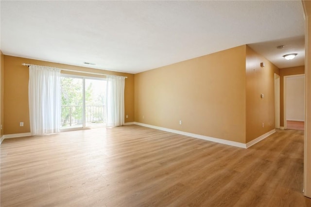 spare room featuring baseboards and light wood-style floors