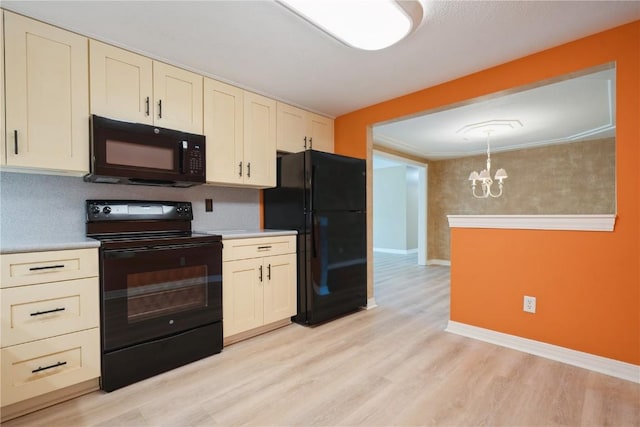 kitchen featuring black appliances, a chandelier, light wood-style flooring, and light countertops