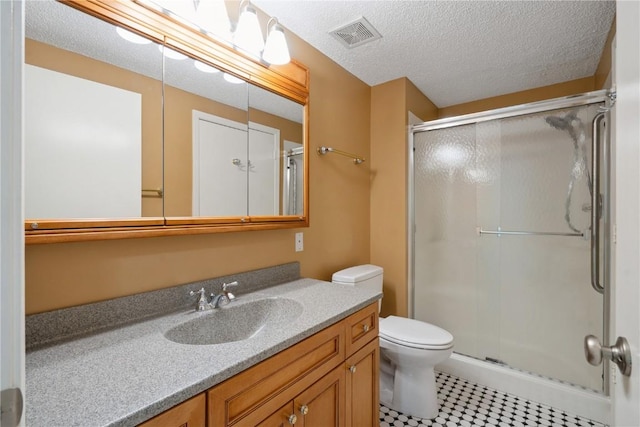 bathroom featuring a shower stall, vanity, toilet, and a textured ceiling