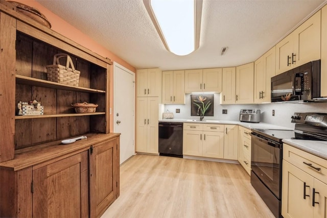 2135 1st Ave SE Unit 215, Cedar Rapids, IA 52403 - kitchen featuring black appliances, light wood-style flooring, light countertops, a sink, and a textured ceiling