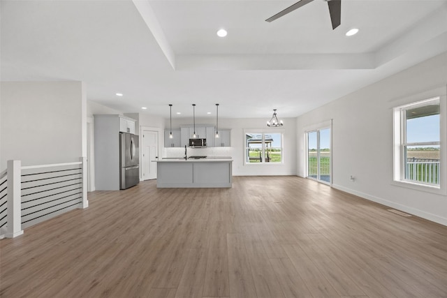 1356 Hickory Ridge Dr, Marion, IA 52302 - unfurnished living room featuring light wood-style flooring, ceiling fan, a chandelier, a raised ceiling, and recessed lighting