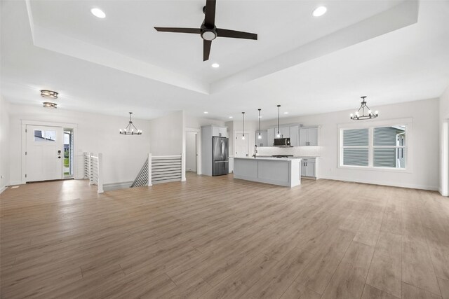 1356 Hickory Ridge Dr, Marion, IA 52302 - unfurnished living room with a chandelier, a tray ceiling, recessed lighting, light wood-style flooring, and ceiling fan