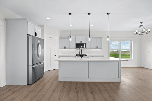 1356 Hickory Ridge Dr, Marion, IA 52302 - kitchen featuring stainless steel appliances, light countertops, decorative backsplash, light wood finished floors, and a kitchen island with sink