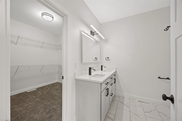 1356 Hickory Ridge Dr, Marion, IA 52302 - bathroom with double vanity, marble look tile flooring, baseboards, and a walk in closet