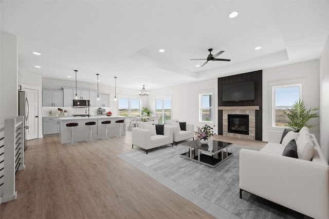 1356 Hickory Ridge Dr, Marion, IA 52302 - living room featuring a tray ceiling, light wood-style flooring, recessed lighting, a large fireplace, and ceiling fan