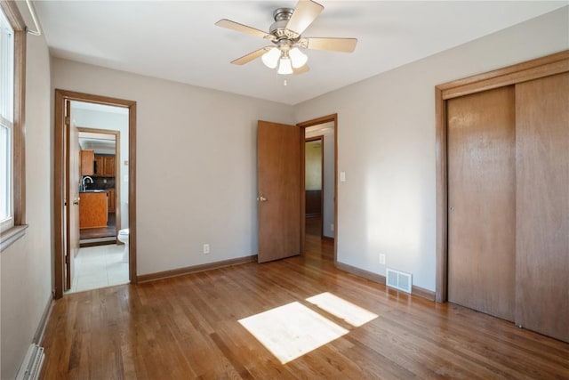 unfurnished bedroom featuring wood finished floors, a closet, and baseboards