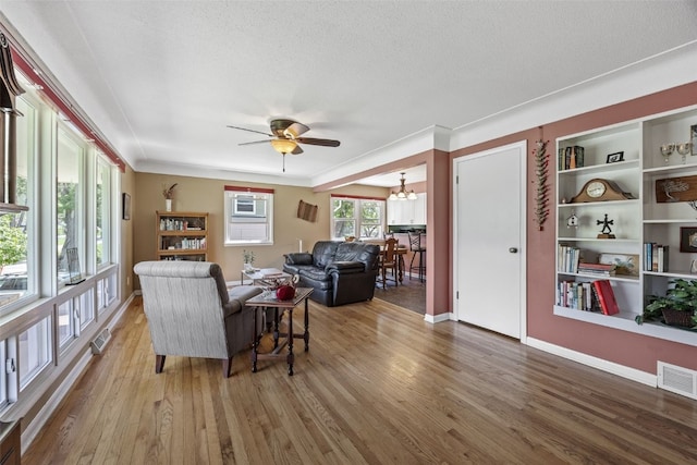 living room with wood finished floors, ceiling fan, a chandelier, baseboards, and a textured ceiling