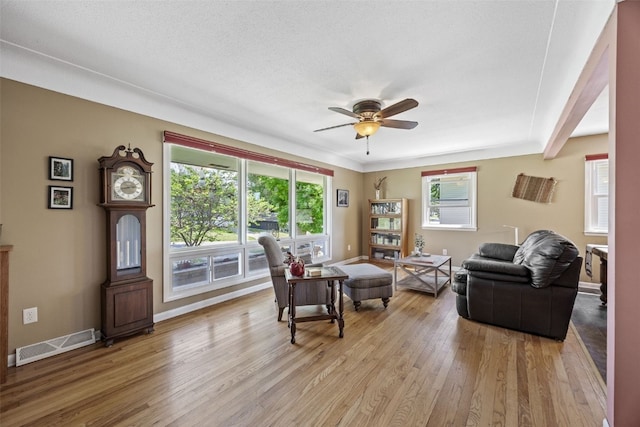 living room with light wood-style floors, a ceiling fan, and baseboards