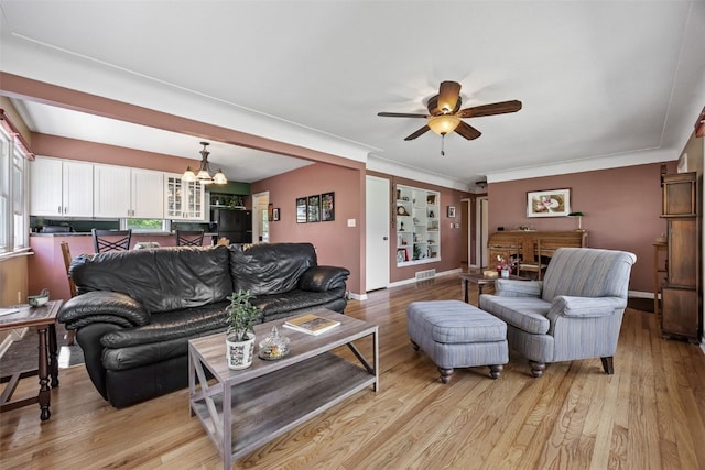 living area featuring ceiling fan, light wood-style flooring, a chandelier, baseboards, and crown molding