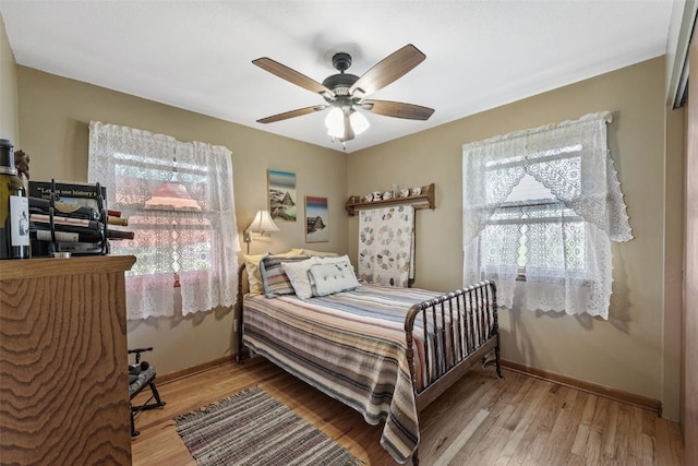 bedroom featuring baseboards, wood finished floors, and ceiling fan