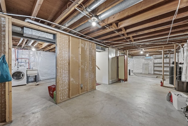 unfinished below grade area with washer / clothes dryer and a sink